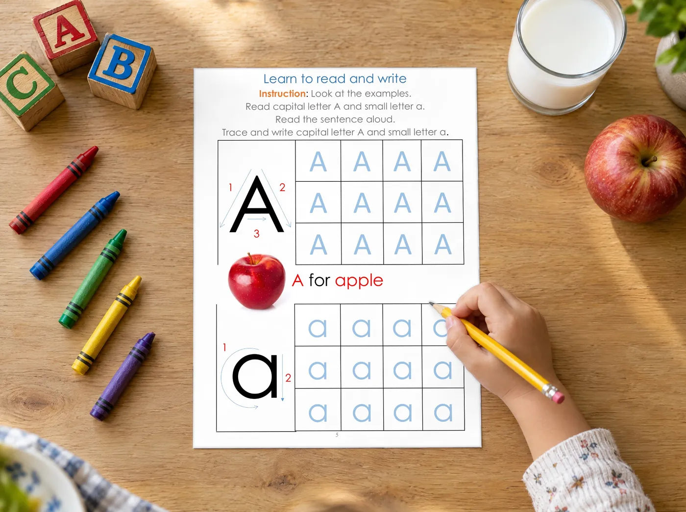 A child's hand with a yellow pencil tracing the A for apple page from the workbook
